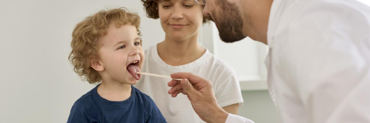 Young boy with mother getting his tongue checked out by a doctor or physician